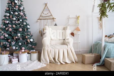 Klassische abgedeckt Sessel neben geschmückten Weihnachtsbaum mit einer Leiter und Dream Catcher an der Wand gehängt. Stockfoto