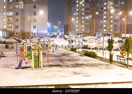 Der erste Schnee in Moskau. Schlafbereich von Moskau. Ein Kinderspielplatz und ein Parkplatz im Schnee. Stockfoto