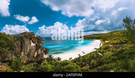 Panoramablick auf den schönen Grand Anse Strand auf La Digue Island auf den Seychellen. Blue Lagoon mit weißen Wolken über Stockfoto
