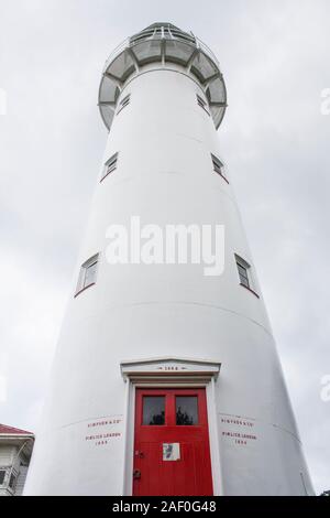 Ältester noch betriebsfähiger Leuchtturm NZ aus Gusseisen, weiß lackiert mit roter Tür. Erbaut 1864 eröffnet 1865. Solarbetrieben. Hauraki Golf, Auckland. Stockfoto