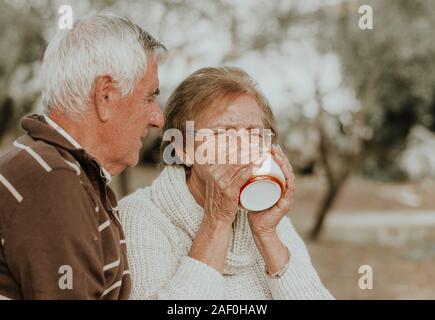 Reife Frau mit Mann trinkt Tee oder Kaffee. Reife Frauen mit Ehemann Tee trinken im Herbst im Freien Szene Stockfoto