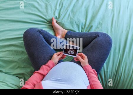 Schwangere Frau sitzen und halten Ultraschallbild. Stockfoto