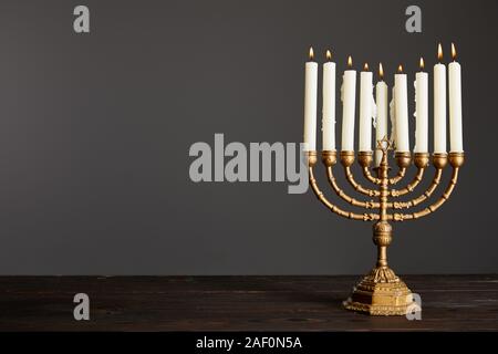 Brennenden Kerzen in der Menorah auf Holztisch isoliert auf Grau Stockfoto