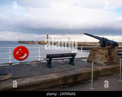 Eine Ansicht von Whitby West Pier von der Batterie Parade unter dem West Cliff mit einem alten Gewehr in Position Stockfoto