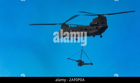 Royal Air Force CH 47 Chinook Hubschrauber mit einem L 118 leichten Artilleriegeschützen underslung Last im Flug Stockfoto