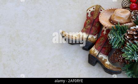 Braun und Beige rustikalen Cowboy Stiefel und Hut mit Weihnachtsschmuck Festlegung auf eine tan Hintergrund mit Kopie Raum Stockfoto