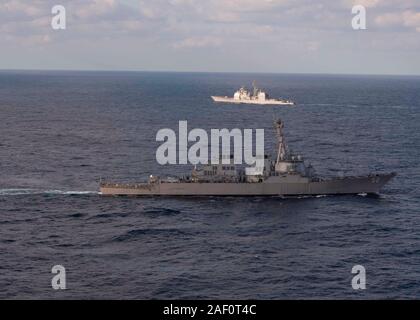 191129-N-OI 558-1251 EAST CHINA SEA (Nov. 29, 2019) Der Arleigh-burke-Klasse geführte Anti-raketen-Zerstörer USS Barry (DDG52) Segel, die sich in der Ausbildung mit der ticonderoga-Klasse geführte-missile Cruiser USS Shiloh (CG67) während einer Manövrieren übung Oberfläche Action Group Aktivitäten zu unterstützen. Silo ist Vorwärts - in die USA 7 Flotte Bereich für Maßnahmen zur Erhöhung der Sicherheit und Stabilität in der indopazifischen Region bereitgestellt. (U.S. Marine Foto von Mass Communication Specialist 3. Klasse Chanel L. Turner) Stockfoto