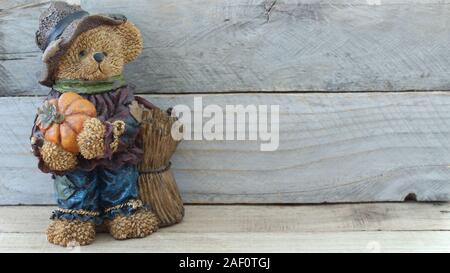 Herbst Teddybär in blauen Overalls tragen ein Bauer hat einen Kürbis stehend auf einem Holz Hintergrund mit Kopie Raum gekleidet Stockfoto