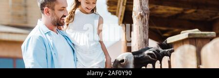 Panorama-aufnahme des glücklichen Vater Holding in die Arme süße Tochter in der Nähe von holzzaun in Zoo Stockfoto