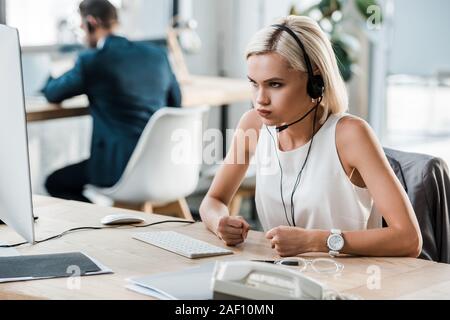 Selektiver Fokus der emotionalen Frau in Headset Gestik im Büro Stockfoto