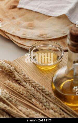 Flache lavash Brot bedeckt mit weißen Handtuch in der Nähe von Schneidbrett mit Spikes und Öl Stockfoto