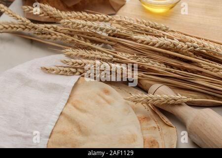 Lavash Brot mit weißen Handtuch in der Nähe von Rolling Pin und Schneidbrett mit Spikes und Öl auf Marmor Oberfläche beschichtet Stockfoto