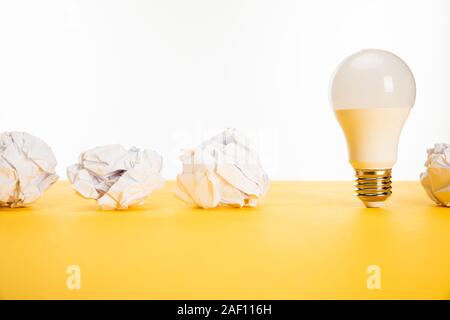 Zerknittertes Papier in der Nähe der Lampe auf der gelben Fläche isoliert auf weißem Stockfoto