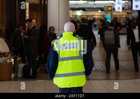 Britischer Grenzkontrollbeamter; britisches Grenzschutzpersonal, das in T3, Flughafen Heathrow, Rückansicht, Flughafen London, Großbritannien arbeitet. Britische Arbeitskraft. Stockfoto