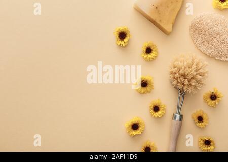 Blick von oben auf die Körper Pinsel, luffa und ein Stück Seife auf beigen Hintergrund mit Blumen und Kopie Raum Stockfoto