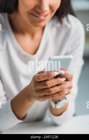 7/8-Ansicht von jungen erwachsenen Frau mit Smartphone in der Wohnung Stockfoto