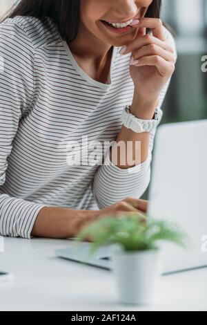 7/8-Ansicht von Frau lächelnd und auf dem Bildschirm des Laptops Stockfoto