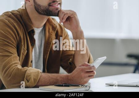 7/8-Ansicht der Mann im Hemd smartphone Holding in der Wohnung Stockfoto