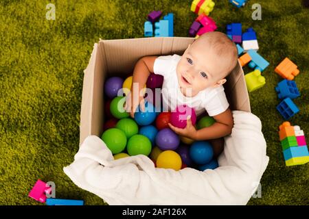 Blick von oben auf die niedlichen Kind im Karton spielen mit bunten Bällen Stockfoto
