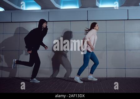 Frau lief weg von Dieb in Hoodie in Unterführung Stockfoto