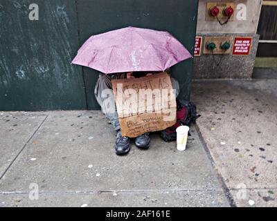 Obdachloser Mann um Geld betteln im Regen am Times Square in New York City Stockfoto