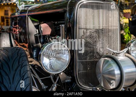 Elegante elegante schwarze alten Vintage Retro Auto mit großen gewölbten Kotflügel und Scheinwerfer und offenen kraftvoller Motor stehend auf einer improvisierten Straße exhibitio Stockfoto