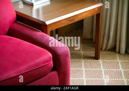 Roten Stuhl neben Holz Beistelltisch Stockfoto