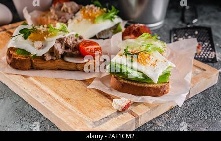 Köstliche Lebertran Sandwiches mit Spiegelei, Salat, Tomaten und Micro Grüns. Leckeres und gesundes Frühstück. Quelle von Omega-3-Fettsäuren. Stockfoto