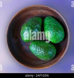 Drei grüne Hass Avocados in eine hölzerne Schüssel. Stockfoto