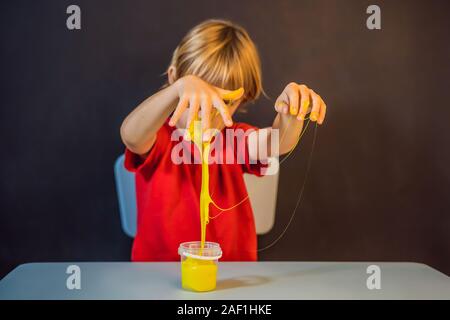 Junge spielt handgemachte Spielzeug namens Schleim. Kind Spiel mit Schleim. Kid squeeze und Stretching Schleim Stockfoto