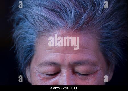 Bangkok, Thailand - 18 April 2011: Konzeptionelle Portrait von älteren Thai Frau mit geschlossenen Augen und graue Haare am Khlong Toei Nachbarschaft, einer armen Gegend o Stockfoto