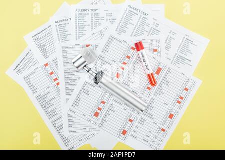 Draufsicht auf das Reagenzglas mit allergietest Schriftzug und dermatoskop auf Allergie test Ergebnisse isoliert auf Gelb Stockfoto