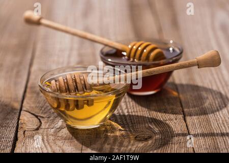 Gläser mit Honig und Honig Schöpflöffel auf Holztisch im Sonnenlicht Stockfoto