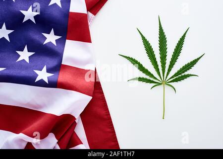 Blick von oben auf die Grüne cannabis Blatt in der Nähe von Zerknitterten amerikanische Flagge auf weißem Hintergrund Stockfoto