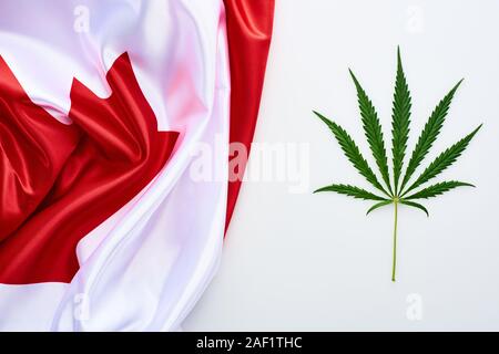 Blick von oben auf die grüne Flagge cannabis Blatt in der Nähe von Kanada auf weißem Hintergrund Stockfoto