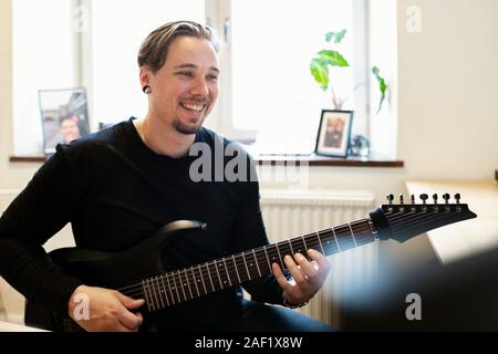 Lächelnd Mann spielt E-Gitarre Stockfoto