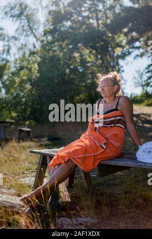 Frau eingewickelt in ein Handtuch entspannend auf der Werkbank Stockfoto