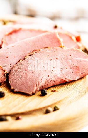 Roastbeef in Scheiben geschnitten. Lecker frisches Fleisch und ganze Pfeffer auf Schneidebrett. Stockfoto
