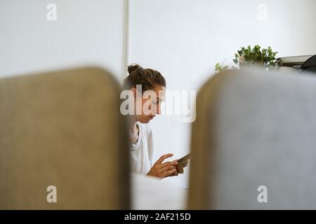 Frau mit Handy im Büro Stockfoto
