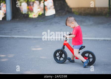 Kleine Junge mit seinem Fahrrad ohne Pedale im Stadion Stockfoto