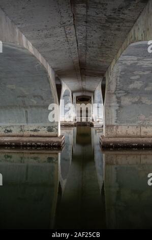 Anzeigen unter einer gewölbten Brücke. Bunte Reflexionen im Wasser Stockfoto