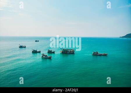 Fischerboote im kristallklaren türkisblauen Wasser des Meeres. Traditionelle kambodschanische Boote gegen den Horizont. Stockfoto