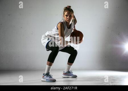 Jungen kaukasischen Frauen Basketball Spieler von Team in Aktion, Bewegung im Run auf weißer Wand Hintergrund isoliert. Konzept für Sport, Bewegung, Energie und Dynamik, gesunde Lebensweise. Ausbildung, üben. Stockfoto