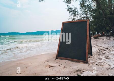 Leere holzschild am Strand. Schwarzes Brett für das Schreiben im Menü Chalk auf weißem Sand am Strand auf einer tropisch-exotischen Insel. Stockfoto