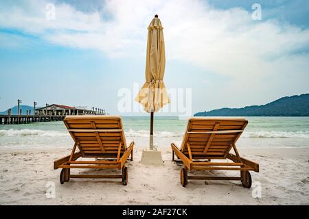 Strand ruhige Szene mit Sonnenliegen und Sonnenschirme Stroh unter Kokospalmen in der Nähe Meer. Tropisches Paradies mit Chaiselounges auf weißem Sand, schöne tra Stockfoto