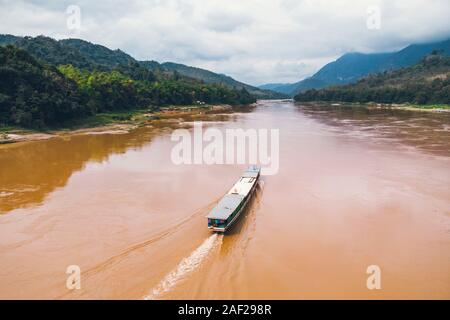 Blick von oben. Beeindruckende Luftaufnahme eines traditionellen Long tail Boot auf dem Mekong Fluss, Luang Prabang, Laos. top Aussicht, Luftaufnahme Stockfoto