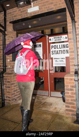 Kidderminster, Großbritannien. 12. Dezember, 2019. Trotz der eisigen Temperaturen und starker Regen, britischen Wähler scheinen in festlicher Stimmung zu sein, wie Sie die Elemente und Kopf zu Großbritanniens Wahllokalen ihre Stimmen in der heutigen Bundestagswahl cast sind mutig. Eine Dame trägt einen saisonalen Santa Hut zum Lächeln bringt und einige dringend benötigte Weihnachtsstimmung zu den Wählern in diesem Worcestershire Wahllokal. Quelle: Lee Hudson/Alamy leben Nachrichten Stockfoto