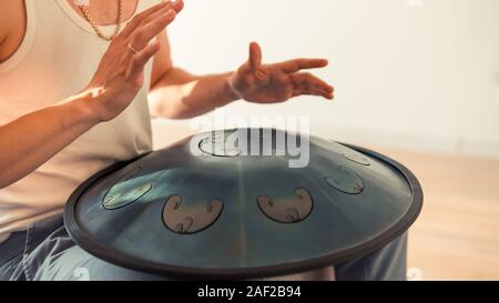 Nahaufnahme des Menschen Hände spielen Hang Drum im Innenbereich. Ungewöhnliche Musik Instrument. Konzept der Sound für die Meditation Stockfoto