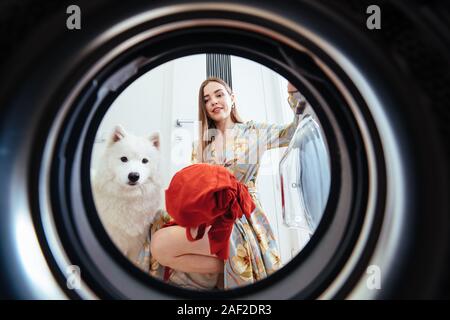 Junge Frau zu Hause setzt das Kleid im Trockner. Stockfoto