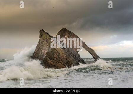 Bogen GEIGE ROCK PORTKNOCKIE Küste von Moray in Schottland stürmischen WINTER WETTER DAS MEER MIT GROSSEN WELLEN UND SPRAY AUF DEN FELSEN Stockfoto